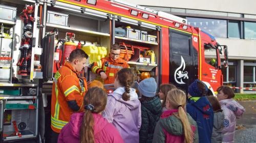 Schüler*innen bekommen ein Feuerwehrauto vorgeführt