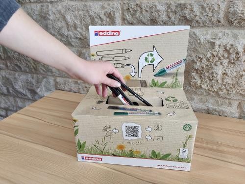 Hand, die zwei Stifte in die Eddingbox werfen