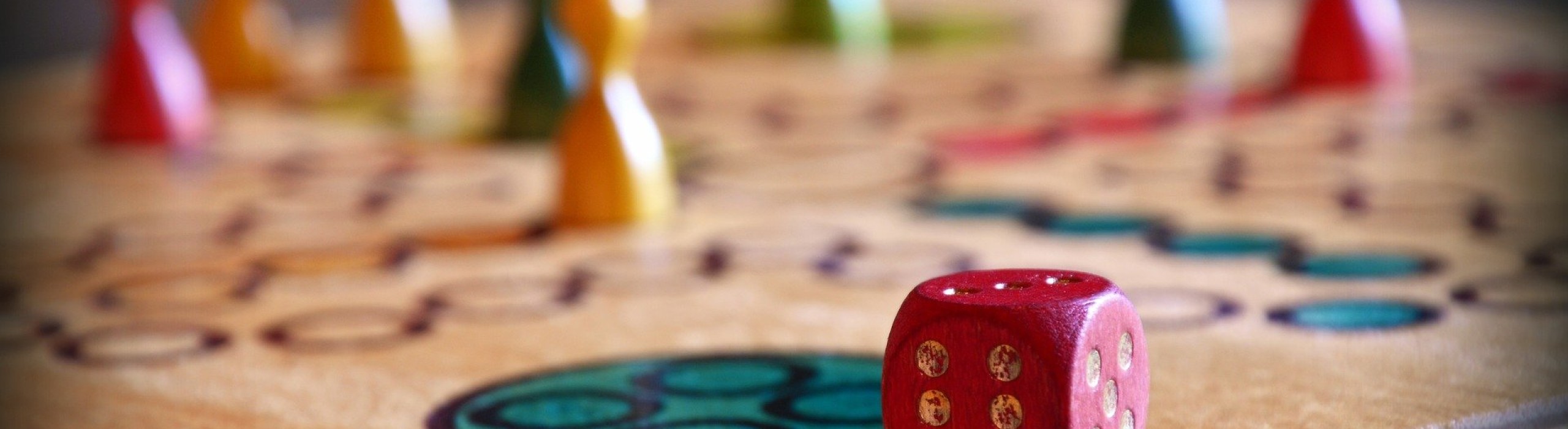 Brettspiel, im Vordergrund der Würfel, im Hintergrund Spielfiguren