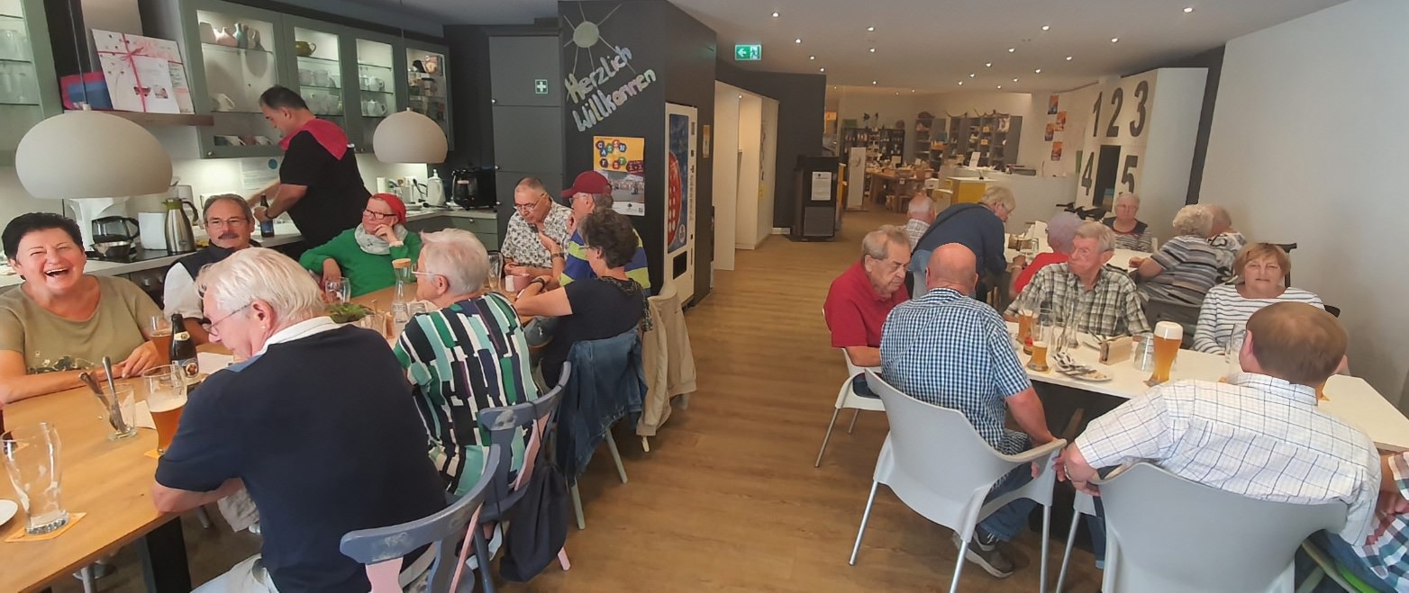 Menschen sitzen zum Weißwurst-Frühstück an Tischen und unterhalten sich