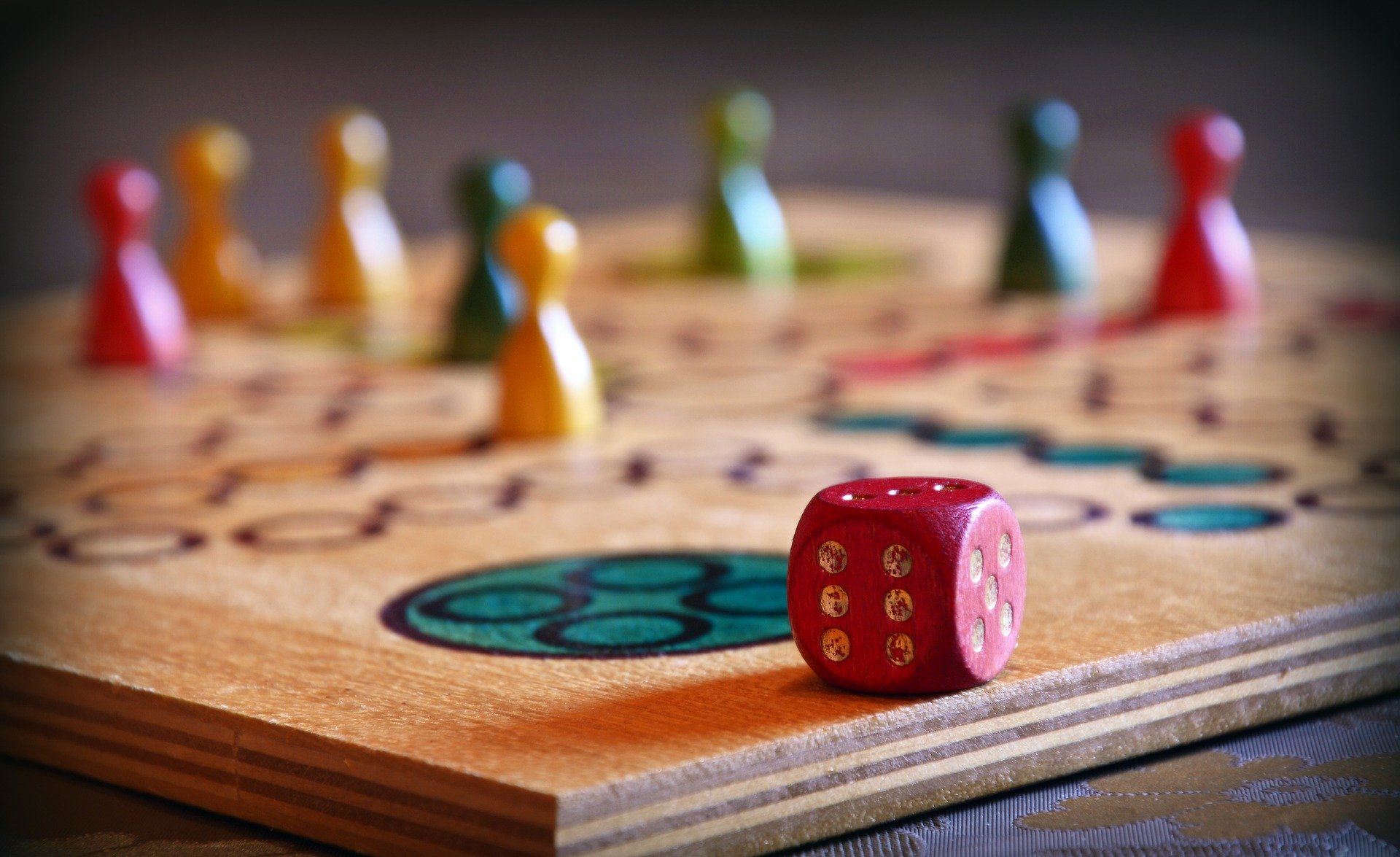 Brettspiel, im Vordergrund der Würfel, im Hintergrund Spielfiguren